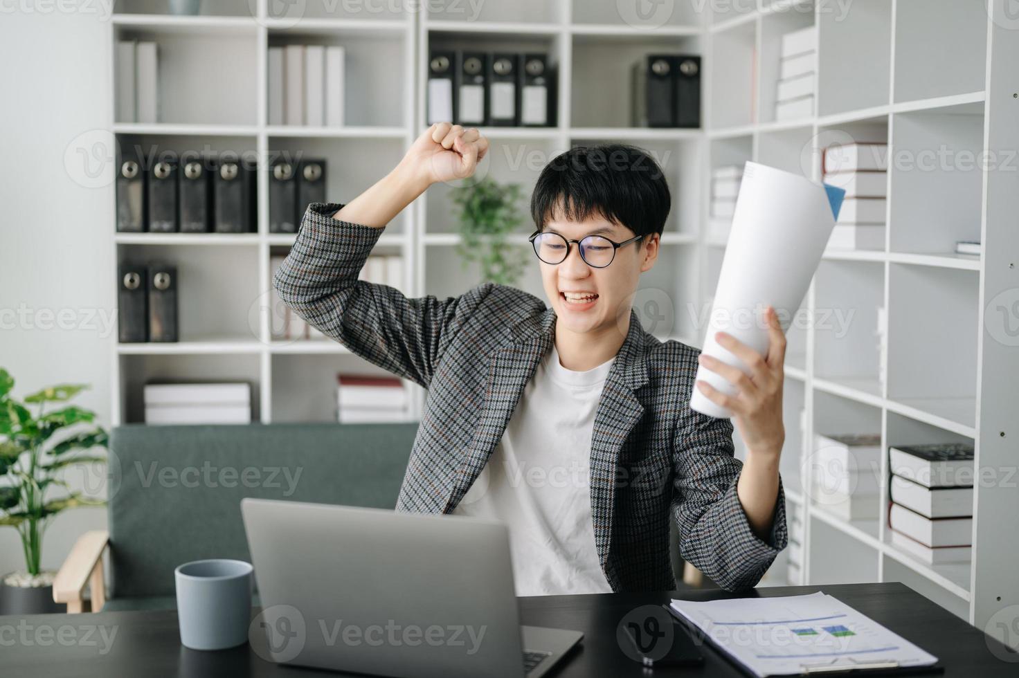 asiatisk företag man är förtjust och Lycklig med de arbete de do på deras läsplatta, bärbar dator och tar anteckningar på de kontor. foto