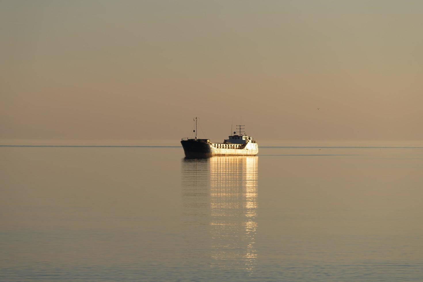 ett ensamt fartyg i ett lugnt hav av gyllene färg. foto