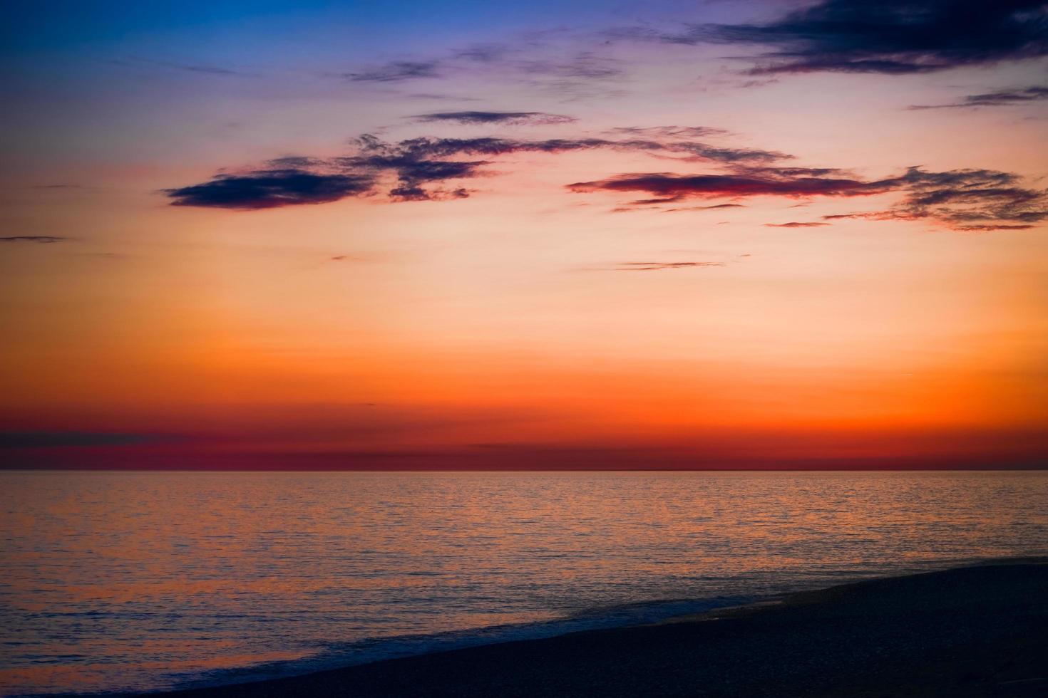 ljus solnedgång över det blå havet med skimrande olika färger i molnen foto