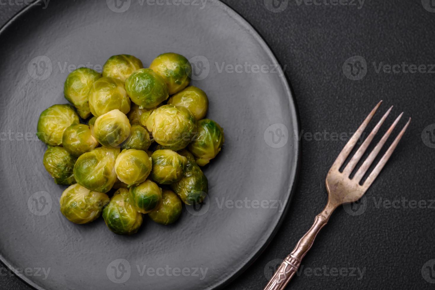 utsökt kokt bryssel groddar på en keramisk tallrik på en mörk betong bakgrund foto