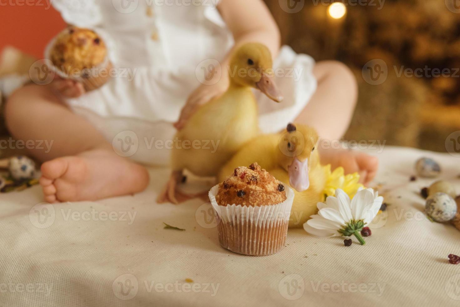 söt fluffig ankungar på de påsk tabell med vaktel ägg och påsk cupcakes, Nästa till en liten flicka. de begrepp av en Lycklig påsk. foto
