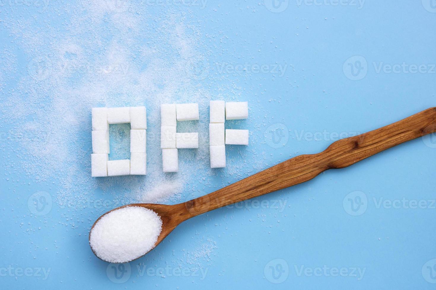 ord av är fodrad med raffinerad socker Nästa till en sked med socker på en blå bakgrund, rätt näring foto