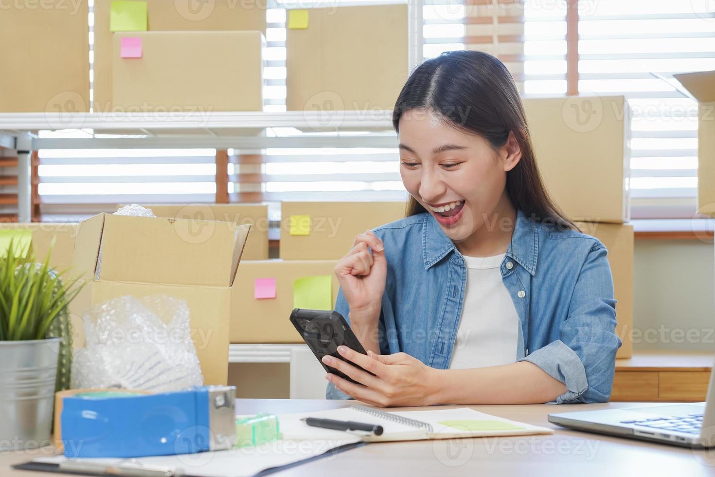 glad små företag entreprenör sme, Lycklig asiatisk ung kvinna ägare leende när motta beställa från kund på app handla förbi smartphone, mobil. handlare uppkopplad, e-handel arbetssätt på Hem kontor. foto