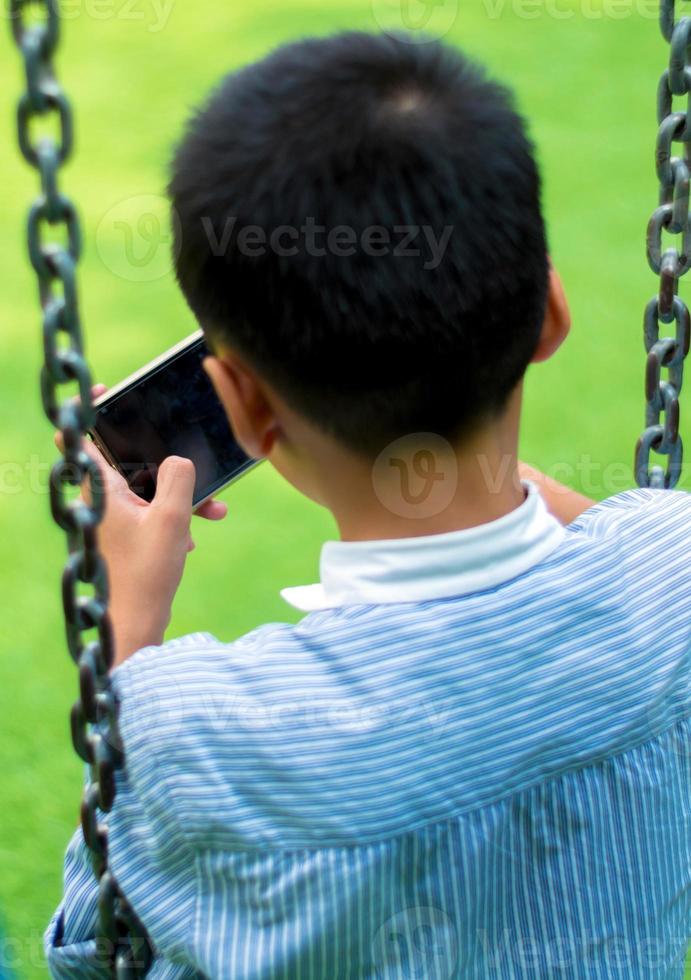 asiatisk pojke spelar spel på smart telefon foto
