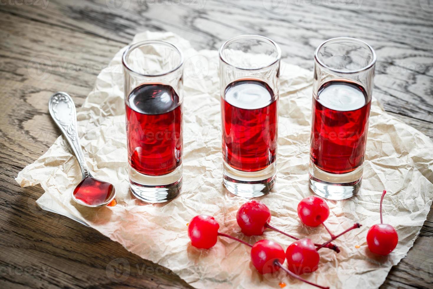 glas körsbärsbrandy med cocktailkörsbär foto