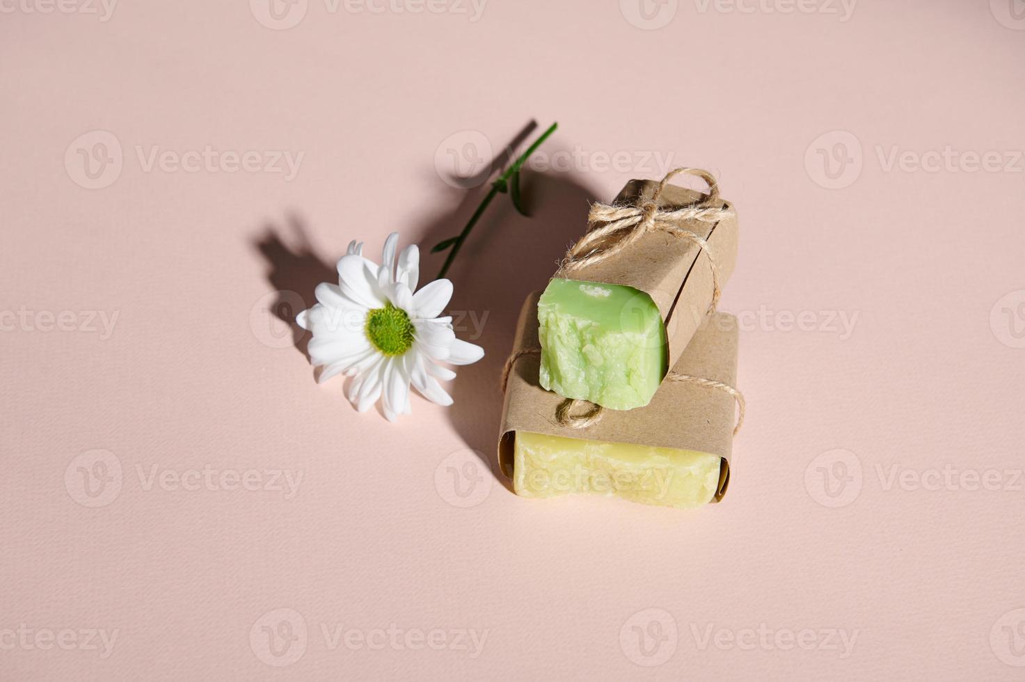 handgjort ekologiskt vänlig tvål barer med naturlig Ingredienser och kamomill blomma, isolerat rosa pastell bakgrund foto