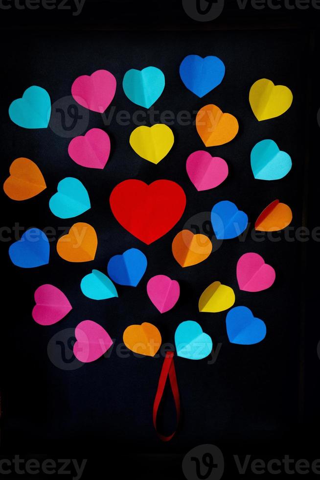 färgrik skära ut papper hjärtan på en svart slät bakgrund foto