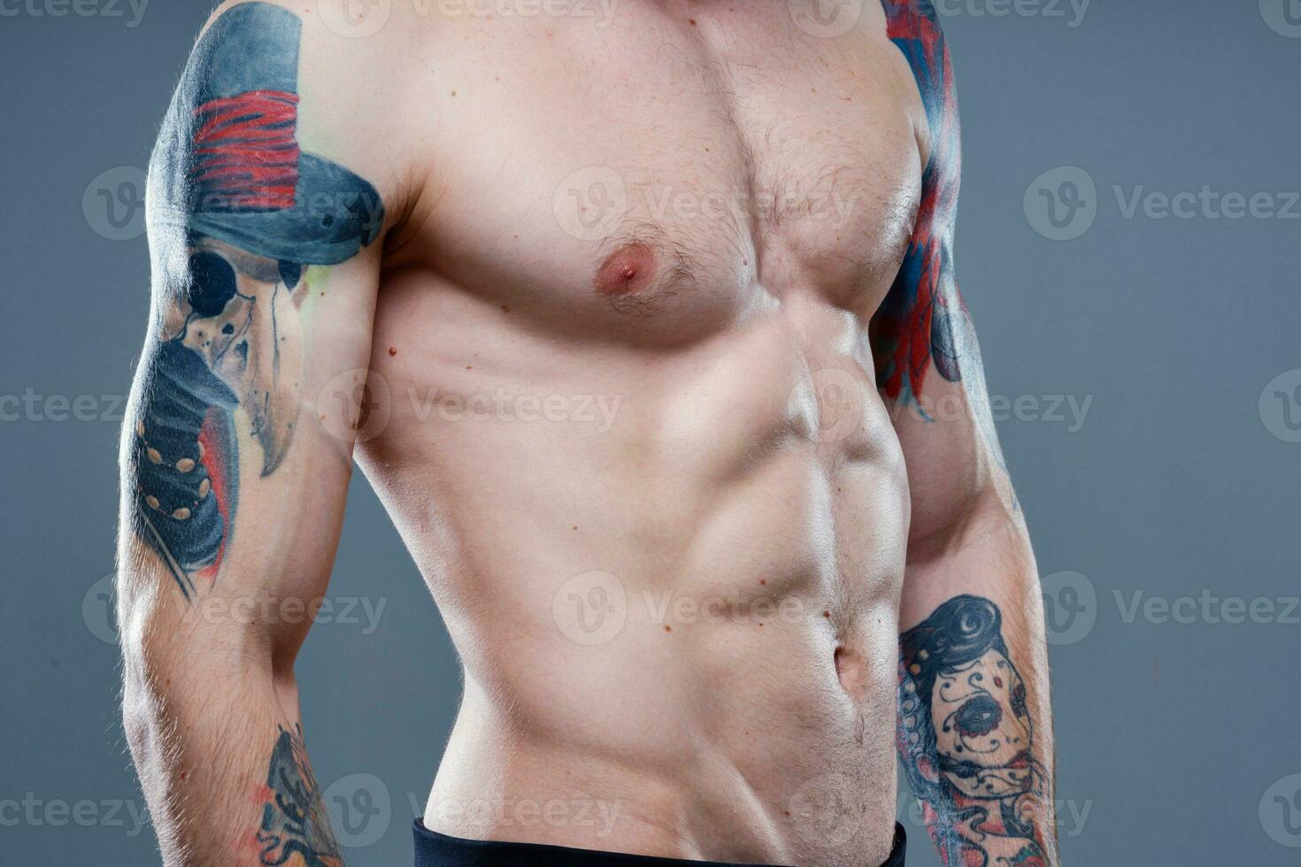 sexig idrottare med naken torso och pumpade upp muskler tatuering grå bakgrund modell foto