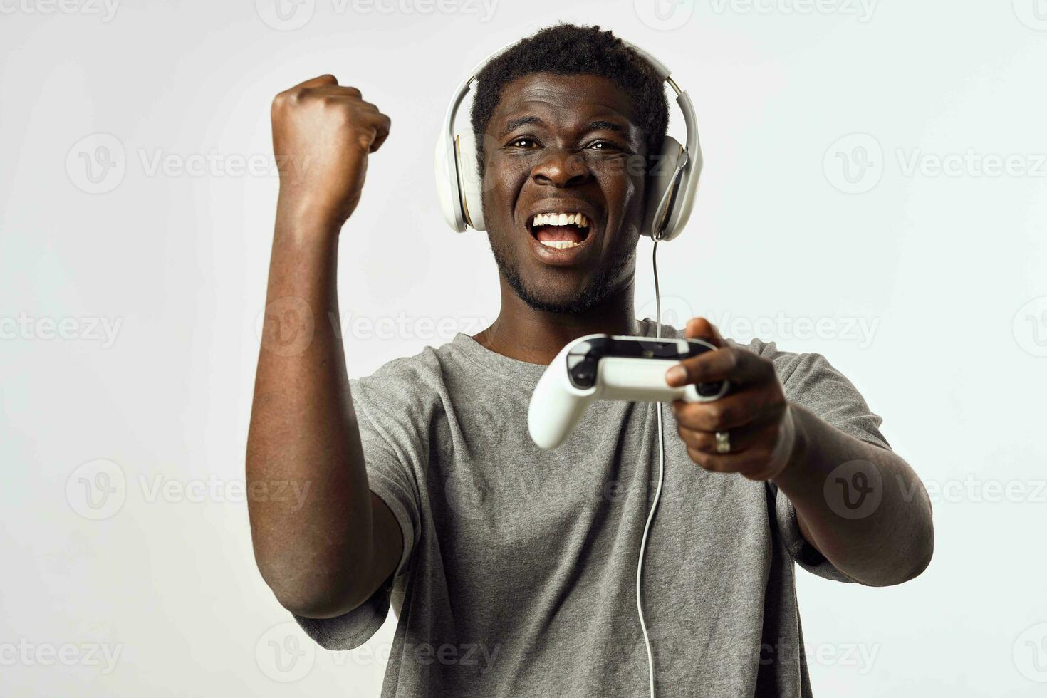 en man av afrikansk utseende i hörlurar med en gamepad i hans händer spelar video spel teknologi foto