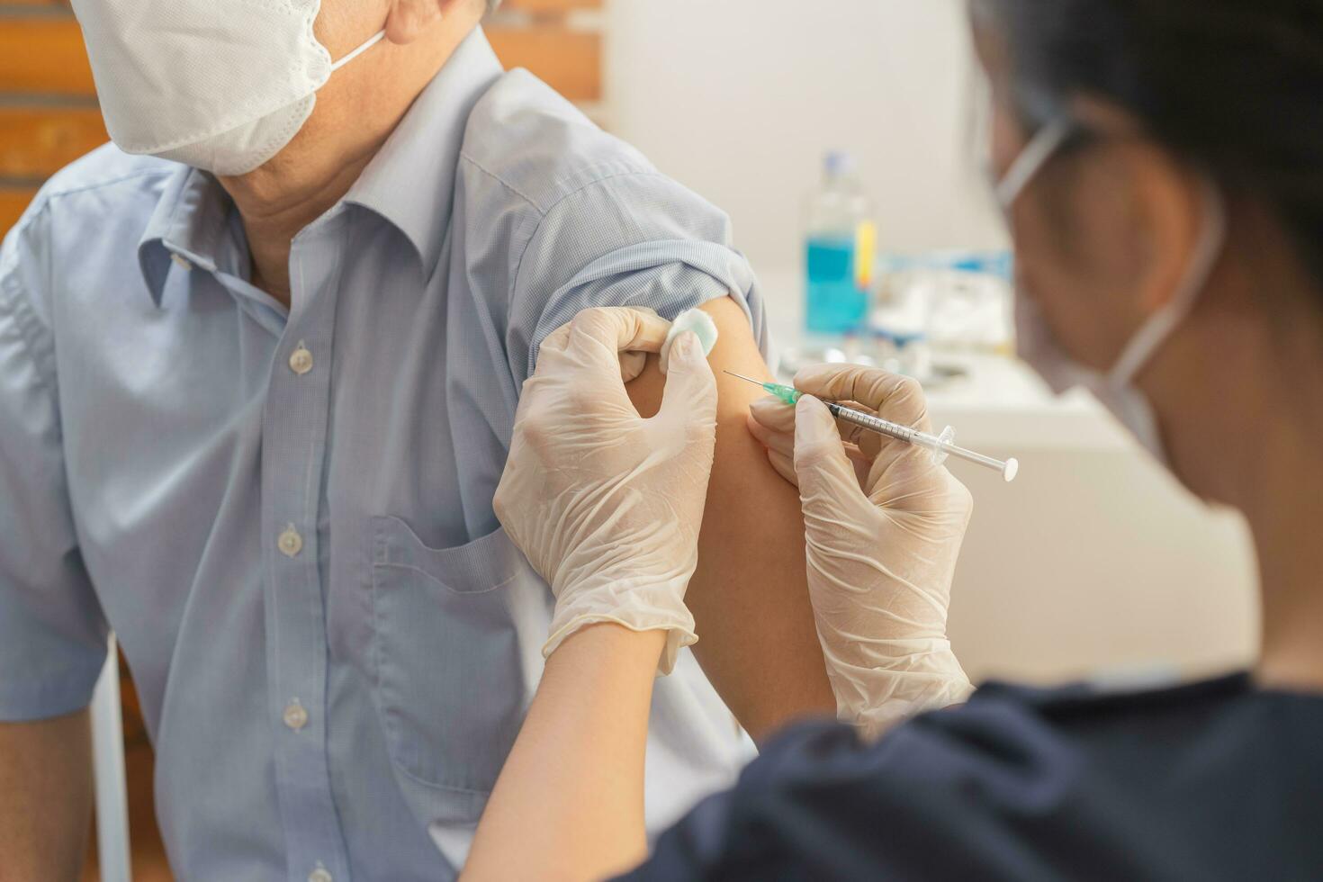 covid-19, coronavirus, äldre asiatisk vuxen man få vaccin från läkare eller sjuksköterska ger skott till mogna patient på klinik. sjukvård, immunisering, sjukdom förebyggande mot influensa eller virus pandemisk. foto