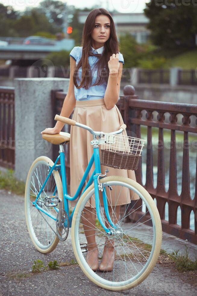 ung vacker, elegant klädd kvinna med cykel foto