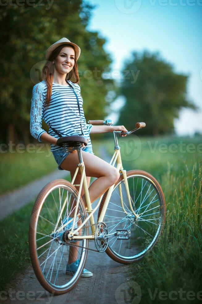 härlig ung kvinna i en hatt med en cykel i en parkera foto