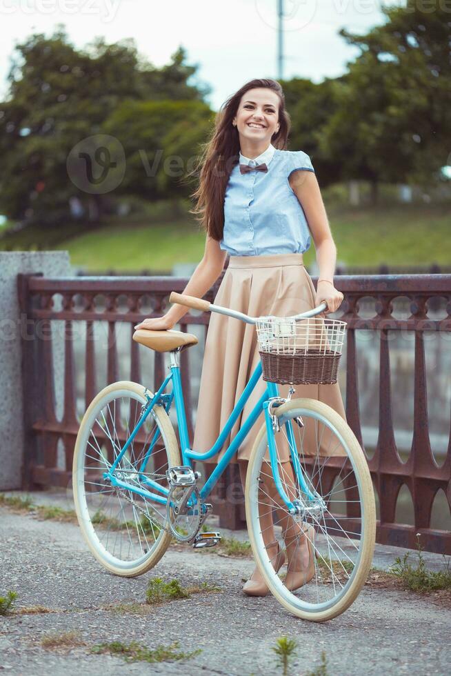 ung vacker, elegant klädd kvinna med cykel foto