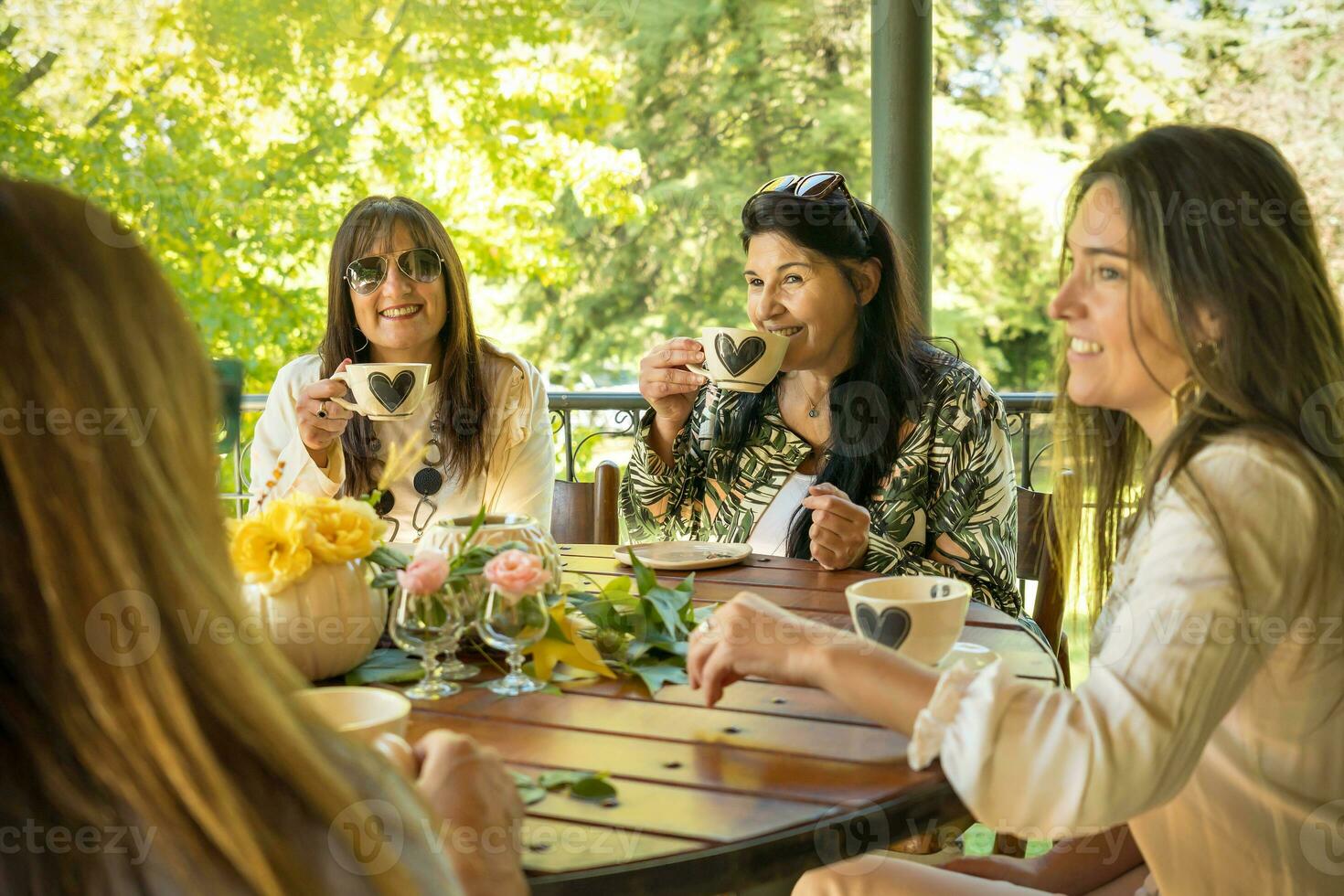 grupp av Lycklig vänner Sammanträde på en runda tabell , dricka te, talande skämt och skrattande. foto
