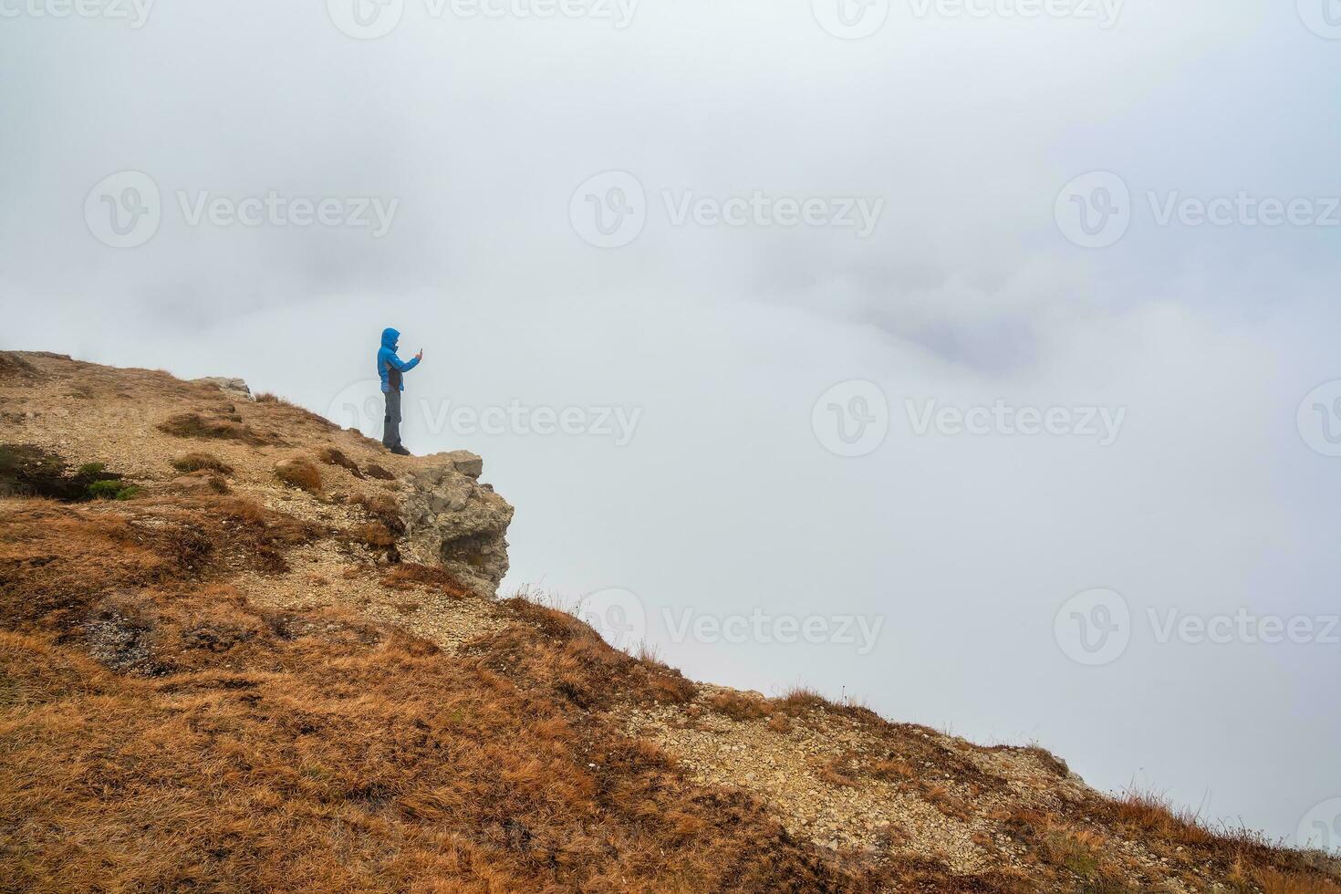 turist tar bilder på berg nära avgrund kant på hög höjd över havet foto