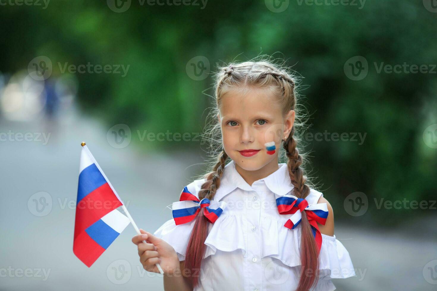 en skola barn står på de utomhus och innehar de flagga av Ryssland. liten flicka med ansikte målning av ryska symbolism. ryska flagga dag. foto