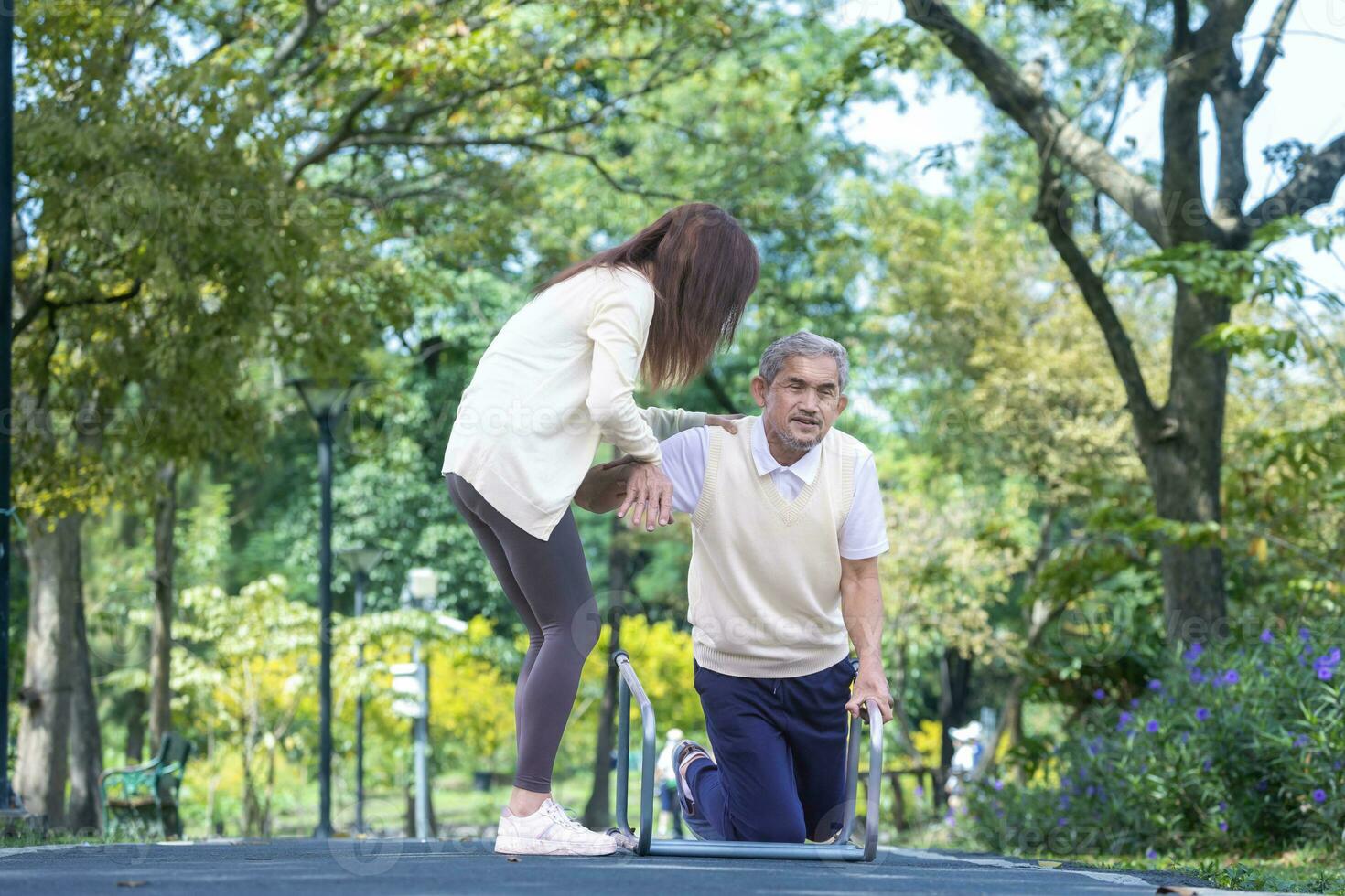 asiatisk senior man är av misstag falla över i de parkera på grund av till de hal väg medan hans niece är lyft honom upp i skada för äldre vård och knä kirurgi återhämtning begrepp. foto