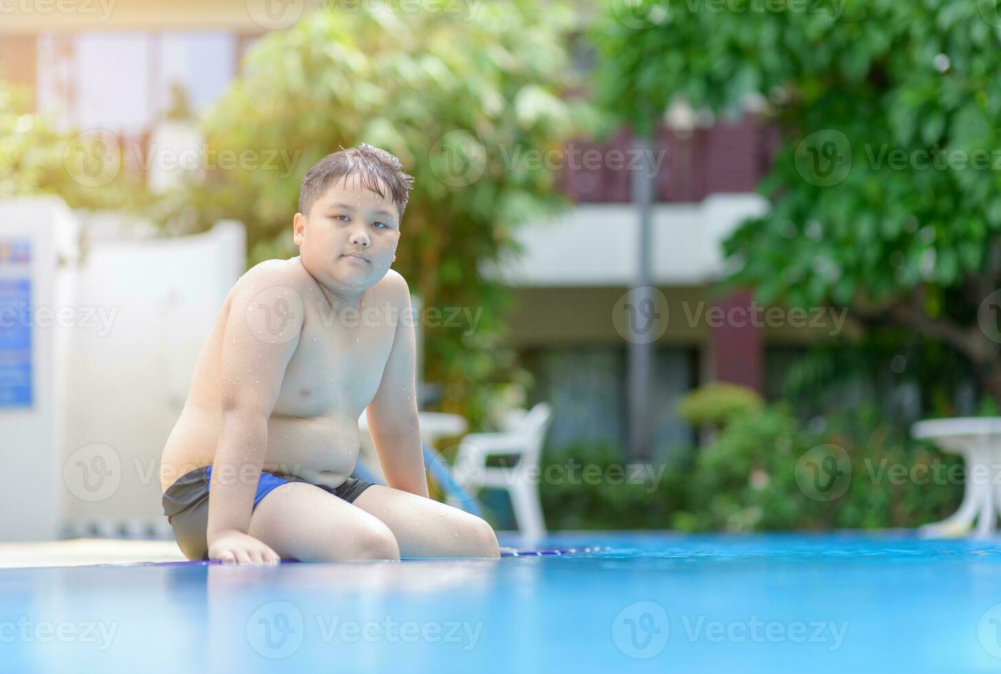 fet fett pojke sitta på simning slå samman, foto