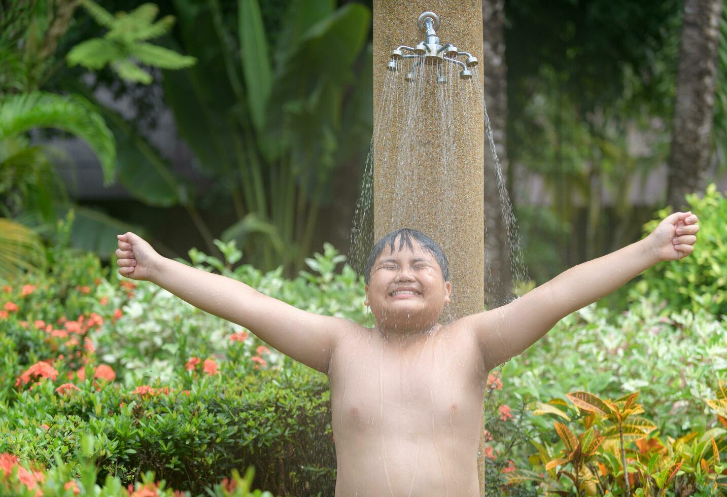 Lycklig fet pojke tar dusch innan simning, foto