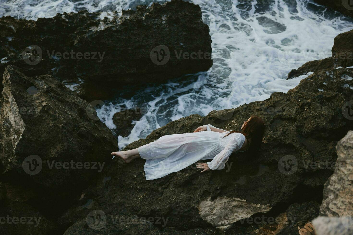 skön ung kvinna i en vit klänning liggande på en sten i en vit klänning oförändrad foto