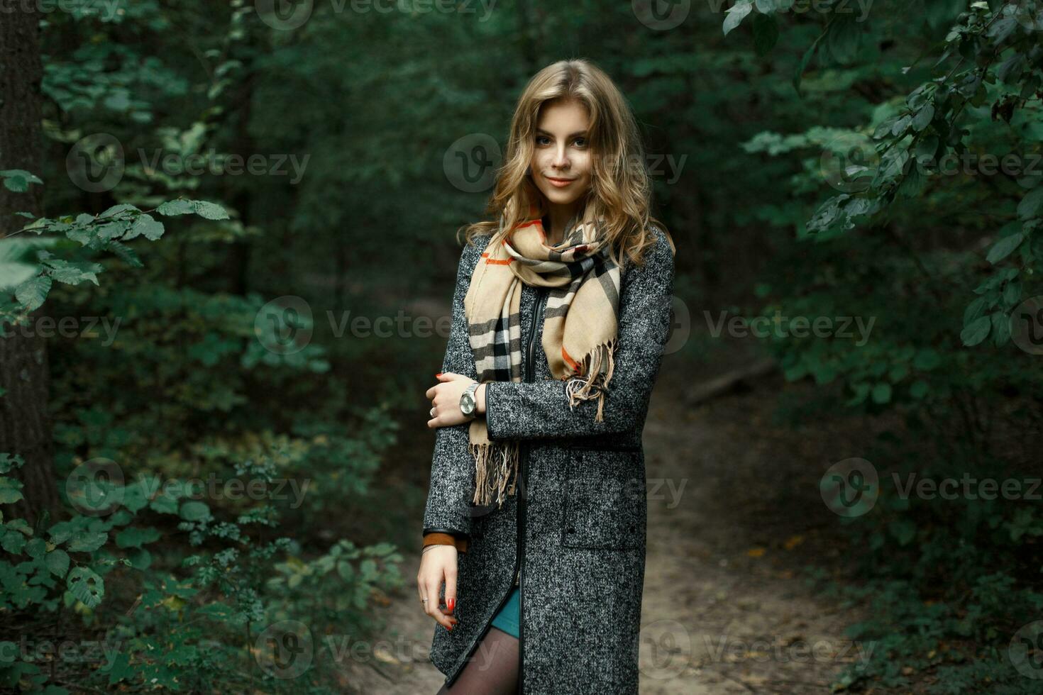 skön flicka i en täcka och scarf i en mörk skog foto