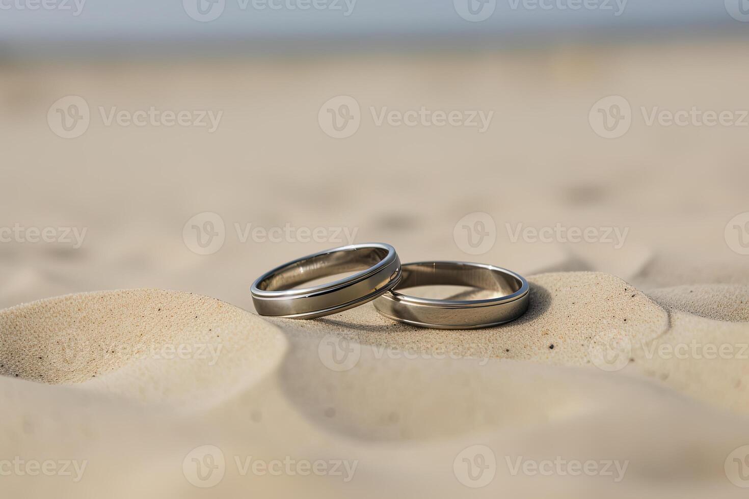 två bröllop ringar i de sand på de bakgrund av en strand och hav. ai genererad foto