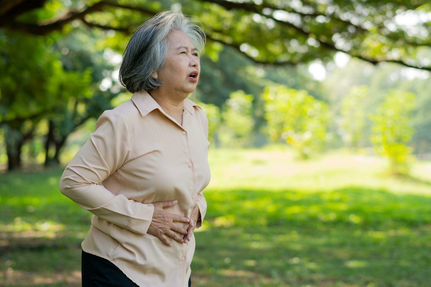 sjuk asiatisk senior kvinna magont eller gastroenterologer, äldre ha en mage problem, akut pankreatit orsak mage värk, symptom mag-tarmkanalen systemet sjukdom, mage, matsmältning problem foto