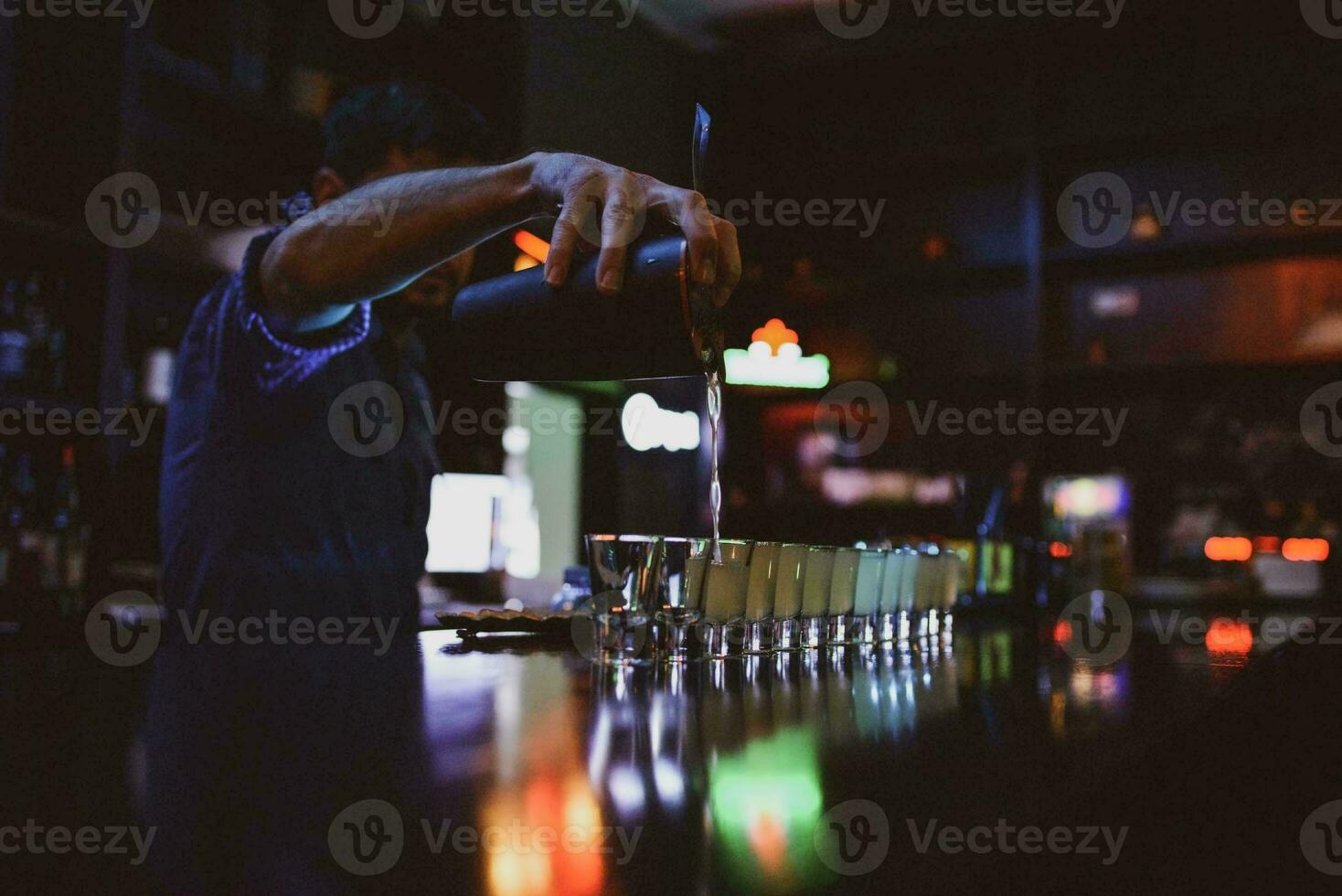 foton illustrerar en bartender fyllning vissa skott glasögon med specifika drycker, Således tändande de atmosfär.