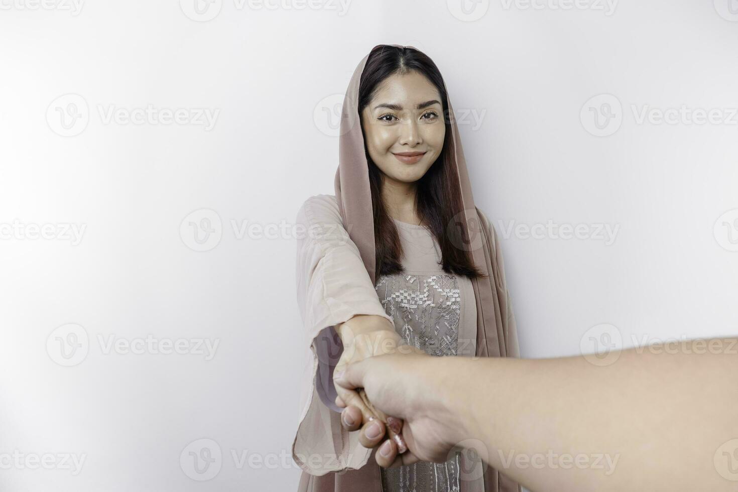 porträtt av en ung skön vänlig asiatisk muslim kvinna bär en slöja gestikulerar handslag eller eid mubarak hälsning foto