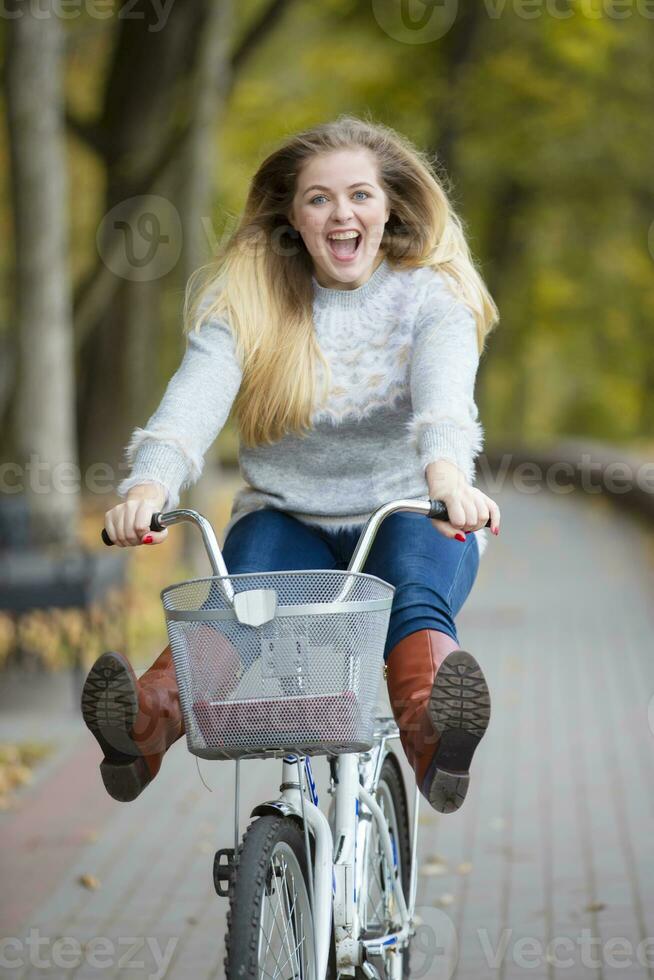 ung skön kvinna rider en cykel i de höst parkera. foto