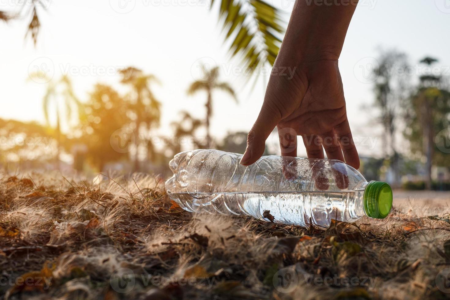 person som plockar upp en plastflaska foto