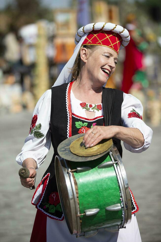 08 29 2020 belarus, lyaskovichi. firande i de stad. äldre slavic kvinna i nationell klänning med en trumma. etnisk ukrainska eller vitryska kvinna musiker. foto