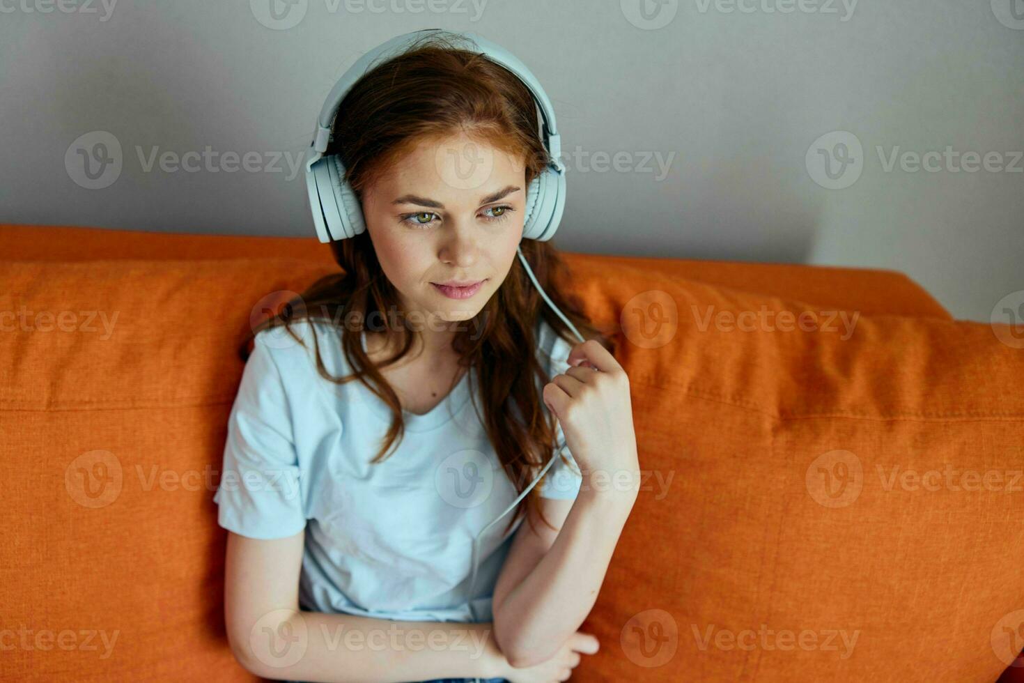 skön kvinna Sammanträde på de soffa på Hem lyssnande till musik på hörlurar teknik foto