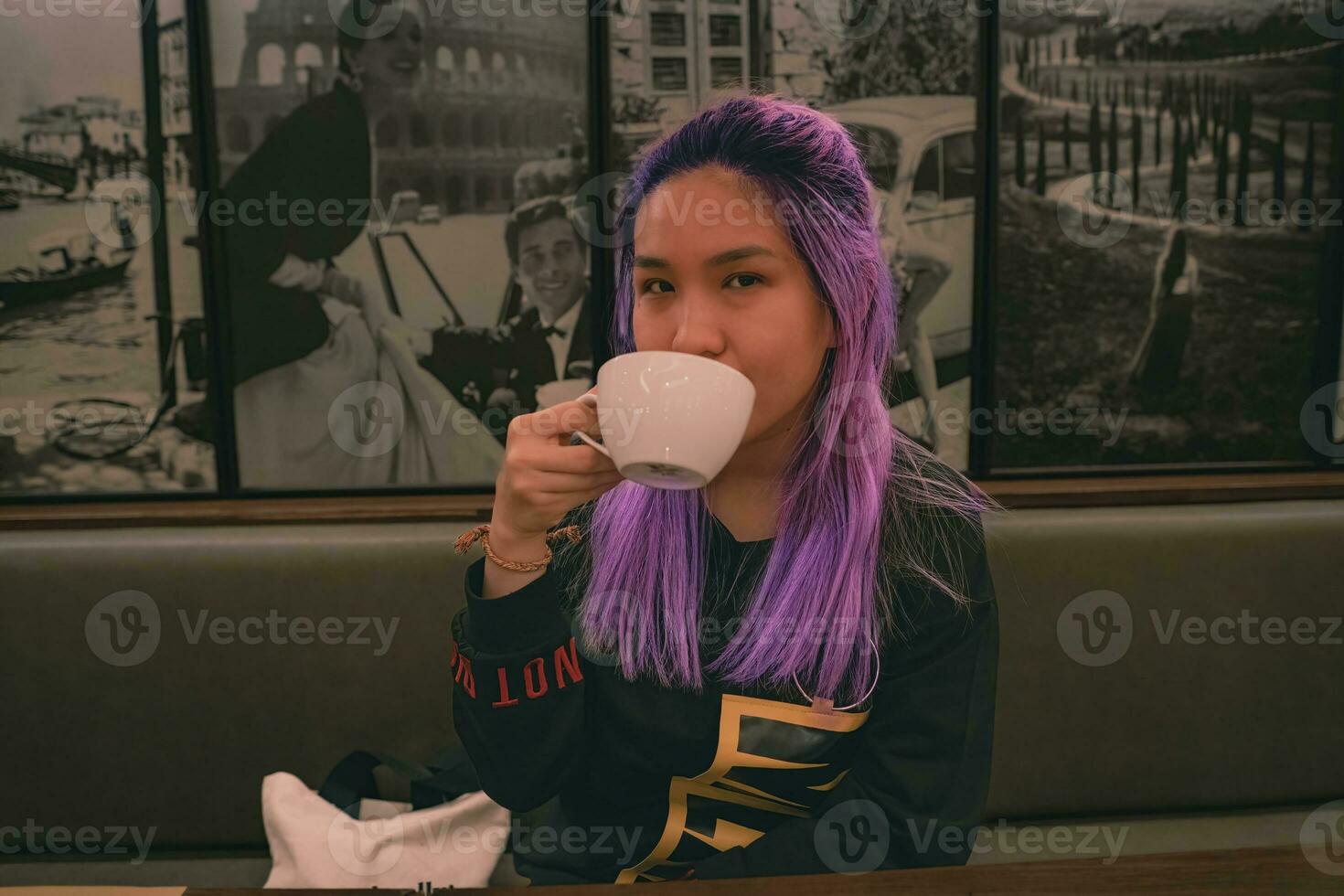 en kvinna med lila hår är dricka te foto