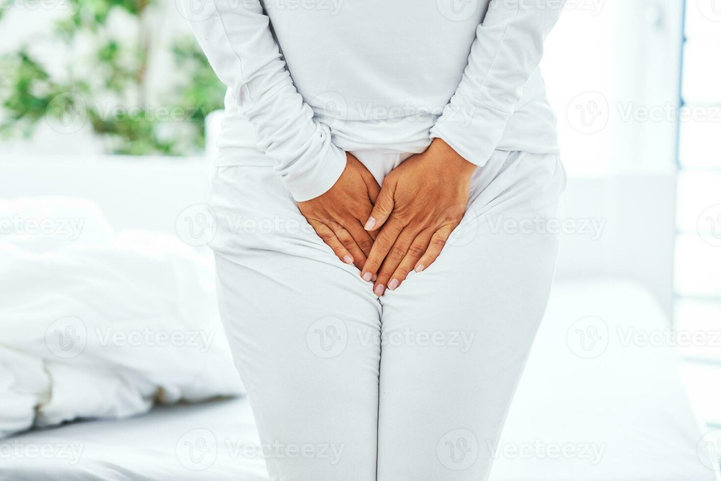 ung brunett kvinna med menstruations- smärta över ljus säng foto