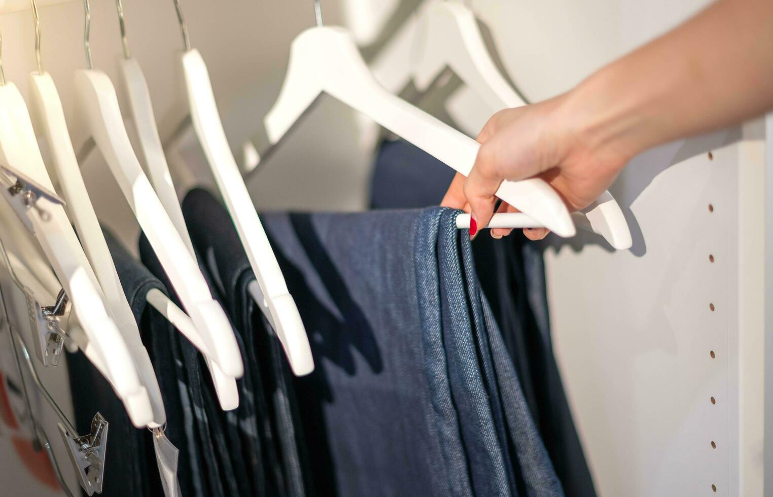 kvinna hand välja kläder för kontrollerade mönster Byxor på de kuggstång i trasa affär på en avdelning Lagra. kolla upp pris, rabatt, och befordran av Kläder Produkter. foto