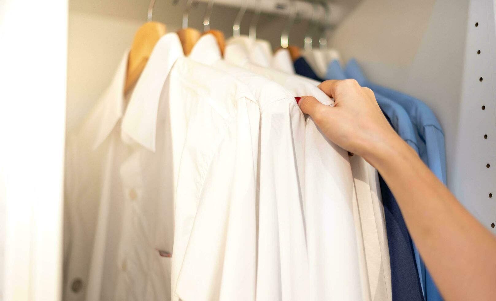 kvinna hand välja kläder för kontrollerade mönster bomull polo skjorta på de kuggstång i trasa affär på en avdelning Lagra. kolla upp pris, rabatt, och befordran av Kläder Produkter. foto