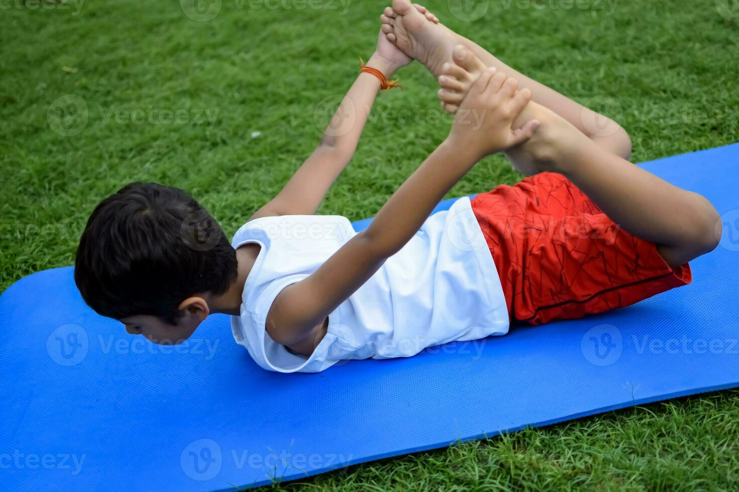 asiatisk smart unge håller på med yoga utgör i de samhälle parkera utomhus, barns yoga utgör. de liten pojke håller på med yoga och meditation träning. foto