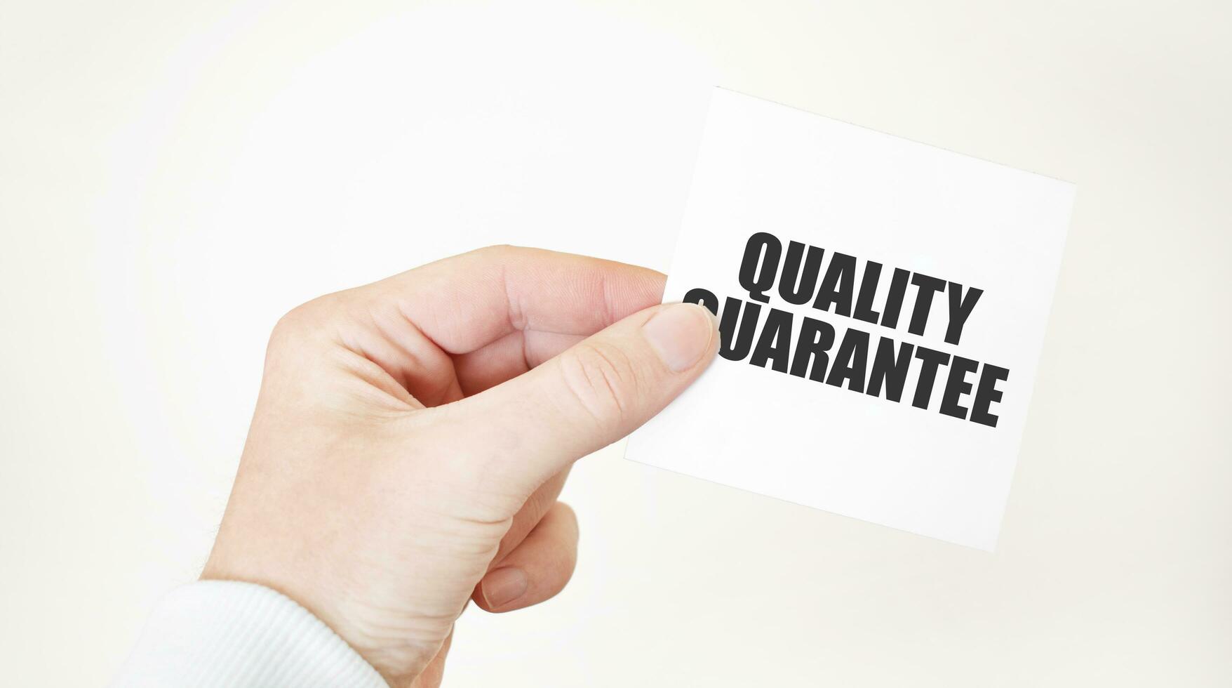 affärsman innehav en kort med text kvalitet garanti, företag begrepp foto