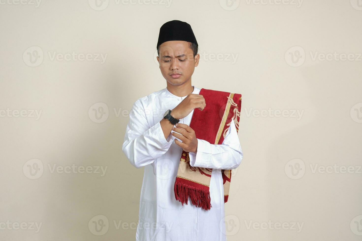 porträtt av attraktiv asiatisk muslim man i vit skjorta ser på handled Kolla på inser den där han är få sent för en möte. isolerat bild på grå bakgrund foto