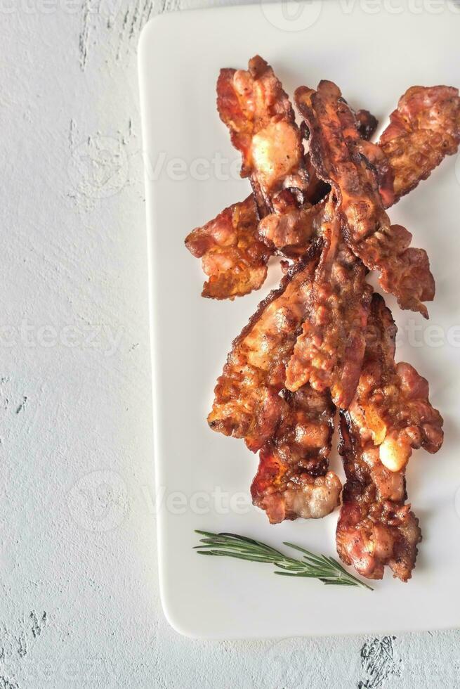 friterad bacon remsor på de vit tallrik foto