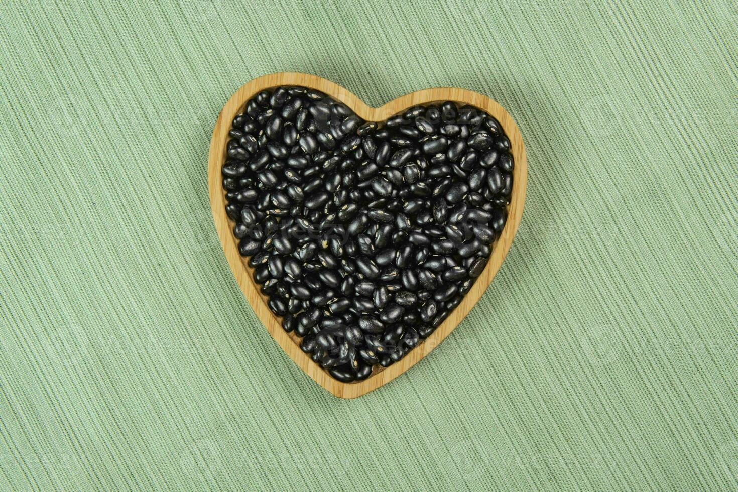 hjärta formad svart böna skål på grön bordsduk foto