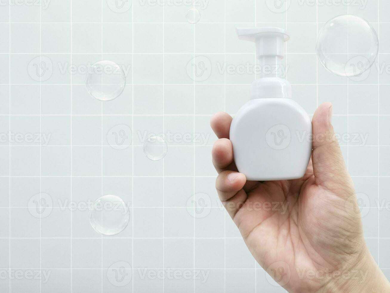 hand innehav en flaska av flytande tvål och tvål bubblor keramisk bricka bakgrund foto