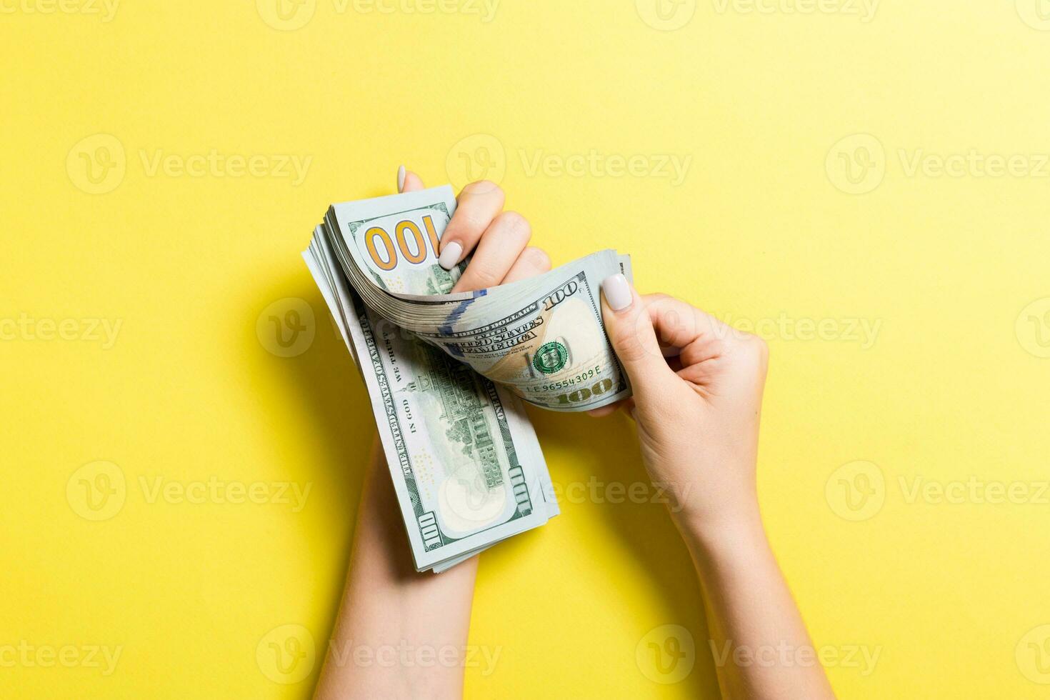 topp se av kvinna händer räkning pengar. ett hundra dollar sedlar på färgrik bakgrund. företag begrepp foto