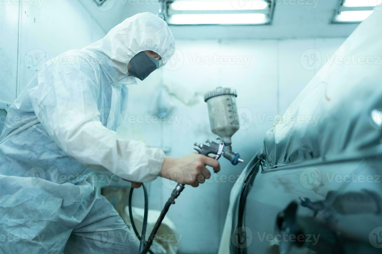 bil mekaniker i bil spray rum använda sig av en spray munstycke injicerad till de sida av de bil kropp med vård till skapa skönhet den där blandningar med de original- Färg av de bil. foto