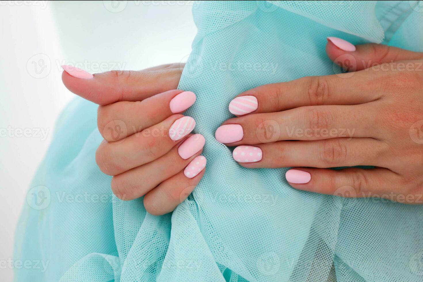 kvinna händer med skön ovalformad naglar, matt rosa manikyr närbild på en blå bakgrund. schellack. kopia Plats foto