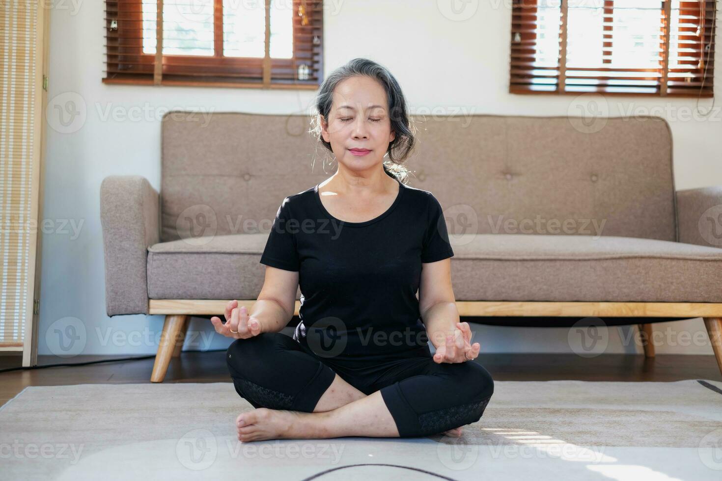 asiatisk äldre kvinna mediterar praktiserande yoga för Bra hälsa på ett äldre ålder, dess handla om tar vård av din kroppens hälsa på Hem på en avkopplande dag. Bra hälsa begrepp foto