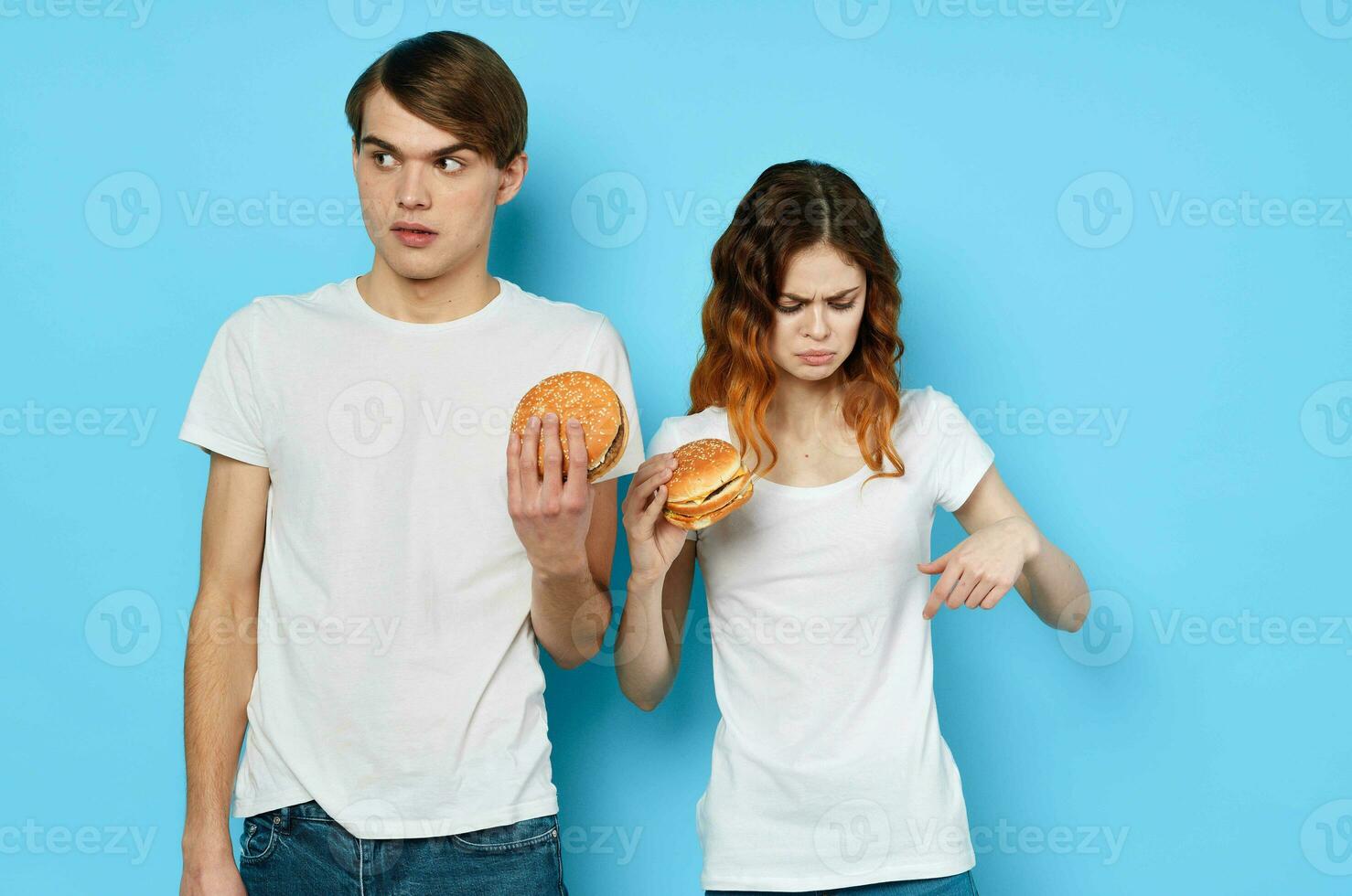ung par med hamburgare i deras händer snabb mat mellanmål skräp mat foto