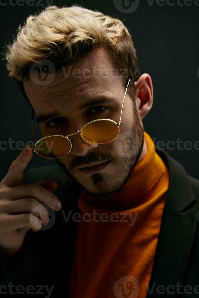 blond man i glasögon på mörk bakgrund och orange Tröja jacka modell foto