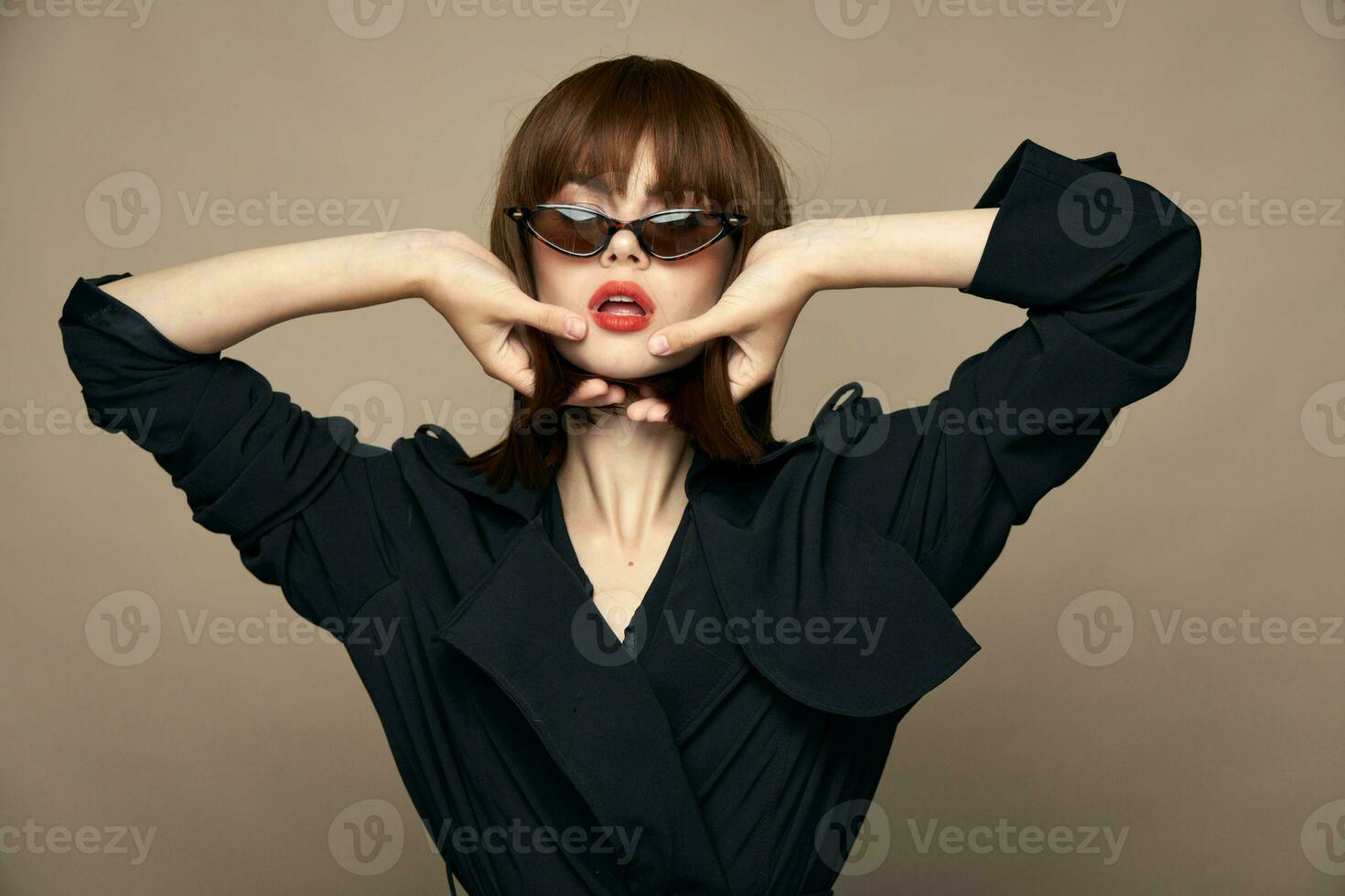 charmig brunett fest modell innehar händer nära ansikte och glasögon röd mun foto